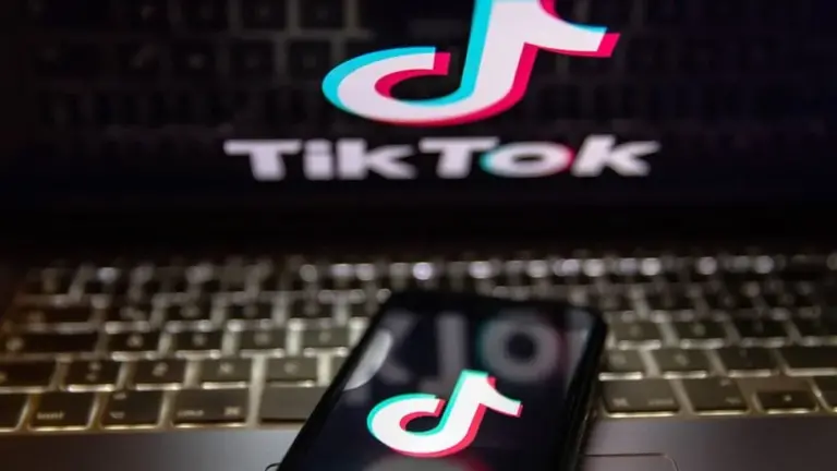 a imagem mostra um celular em cima de um notenook com ambas as telas mostrando o TikTok
